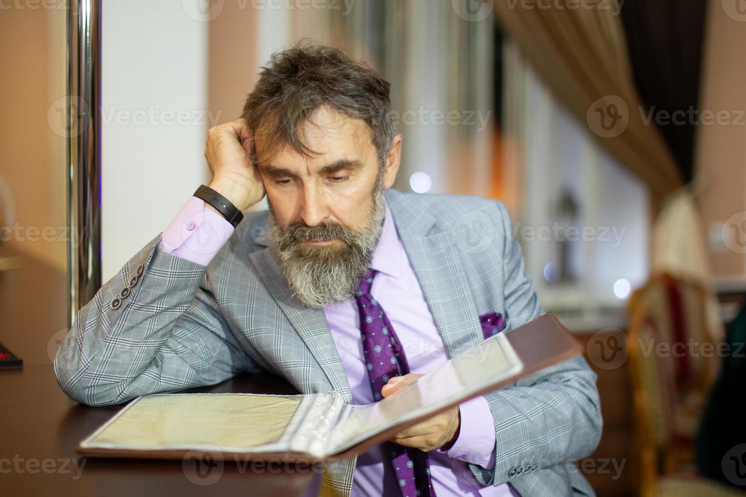 A man with a beard a restaurant client reads the menu. photo