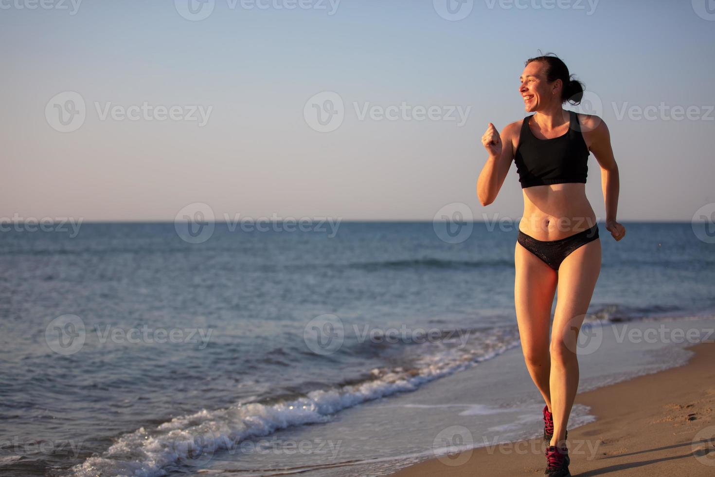 A woman runs along the beach.Jogging along the seashore. photo