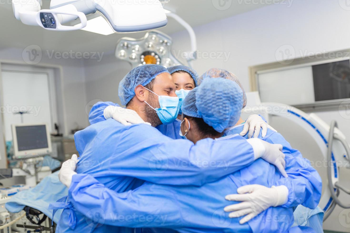 Medical professionals embracing each other in ICU. Doctors and nurses are in protective coveralls after successful treatment. They are at hospital during COVID-19. photo