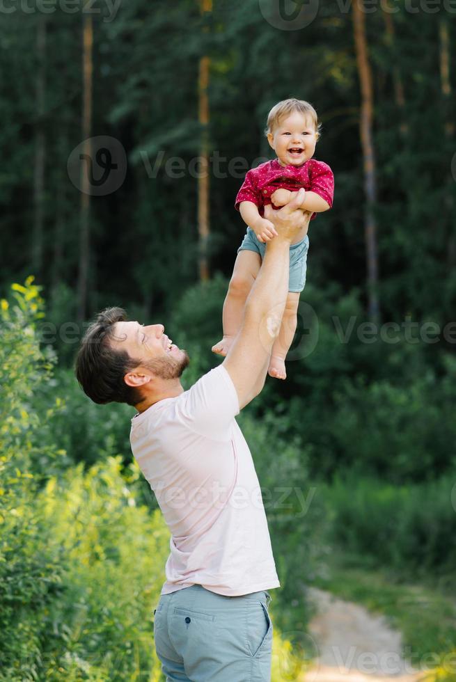 Happy dad having fun with his little son, holding him in his arms at the top photo