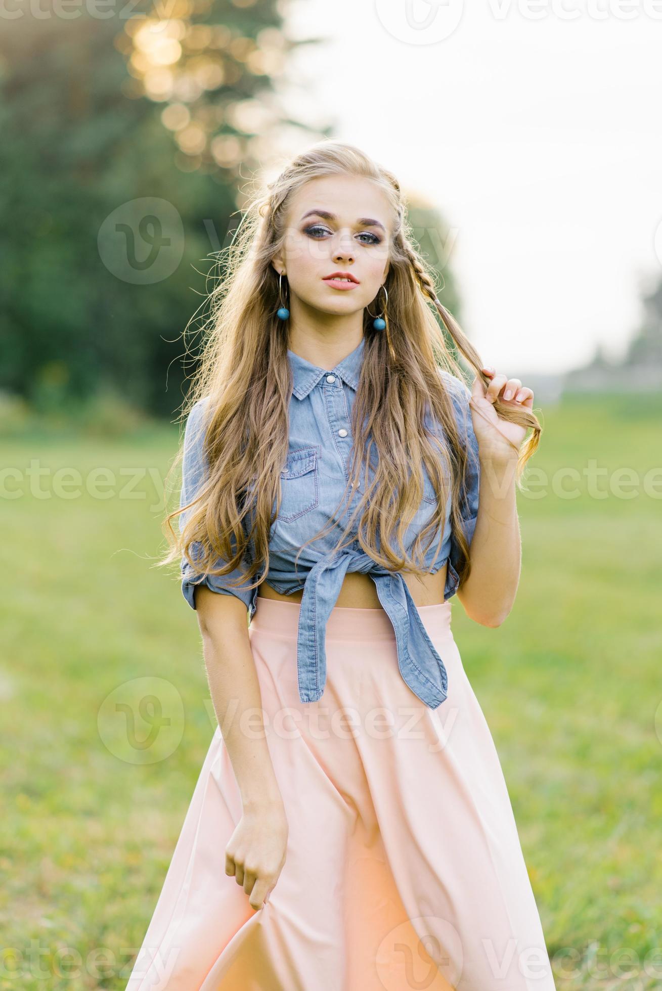 Young Caucasian woman plays with her hair while flirting outdoors in