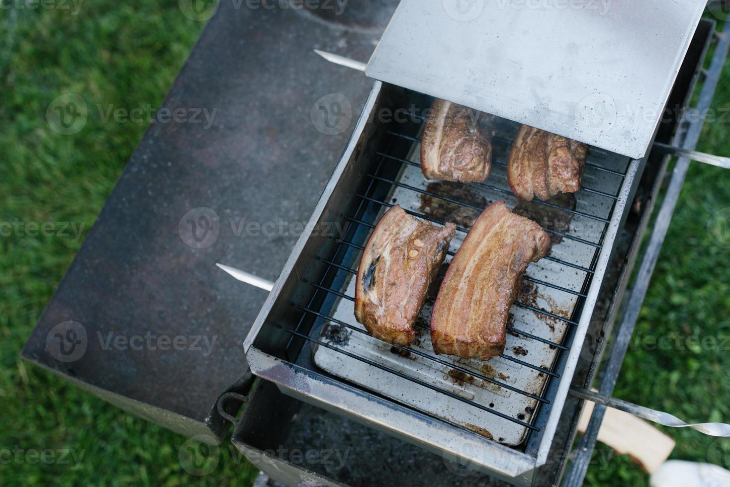 Bacon is smoked in a metal smokehouse in the open air photo