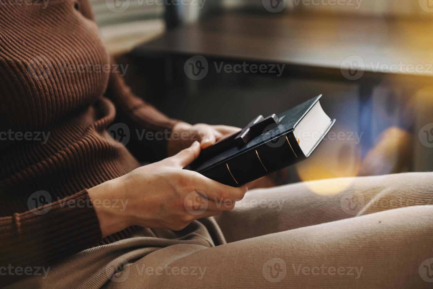 Woman sitting and studying the scriptures.The  wooden cross in the hands. Christian education concepts The Holy Scriptures open photo