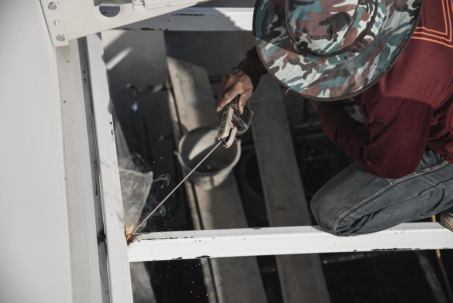 construction man is welding steel roof structure, people working in construction site concept photo