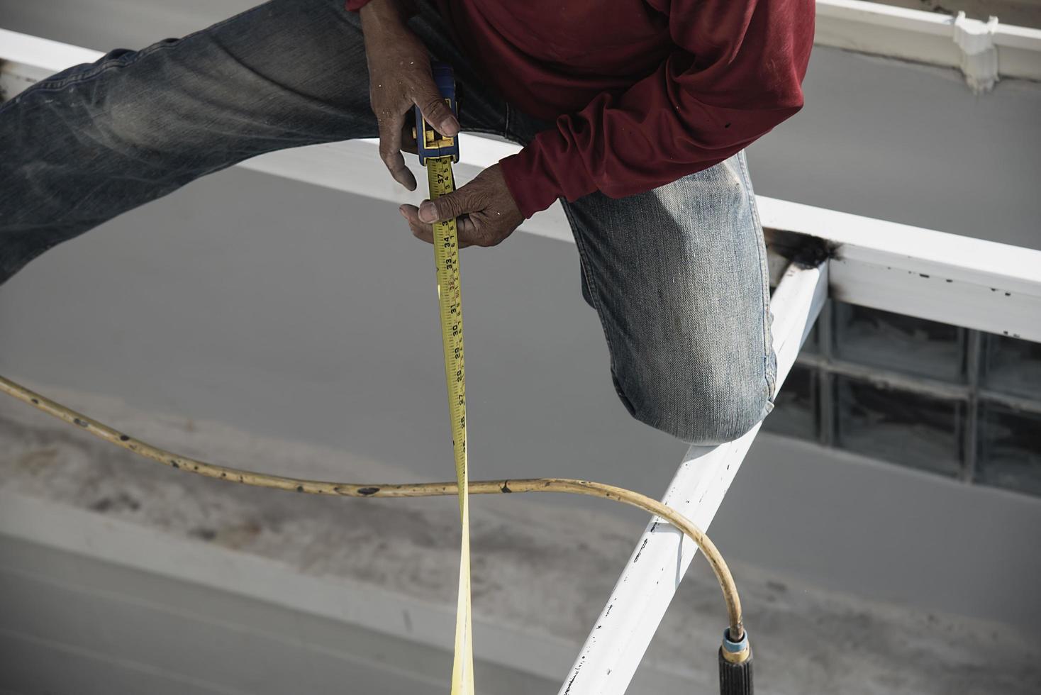 onsite construction worker with steel roof structure installation, residential building contractor job photo