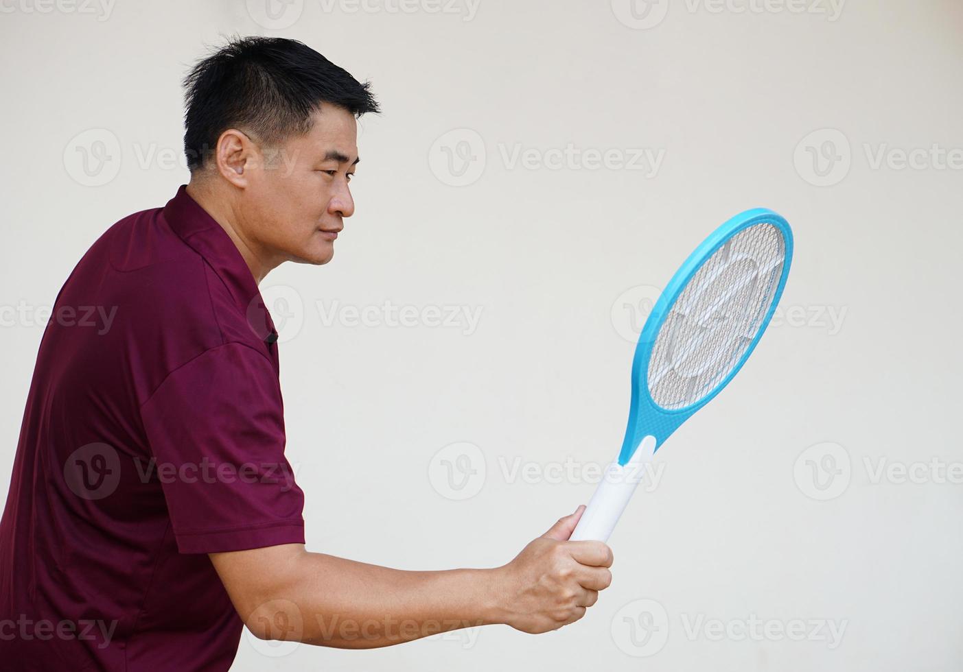 Asian man holds  mosquito electric swatter racket. Concept, Technology electric device to kill mosquitoes, insects, bugs by swatting to flying insects that can cause disease or annoyed feeling. photo