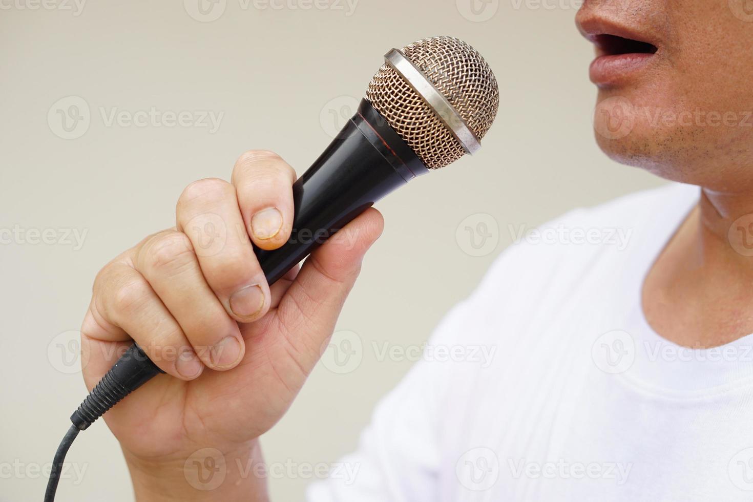 hombre sostiene y hablar o canta en micrófono. concepto, herramienta o dispositivo tecnología ese traduce sonido vibraciones en el aire dentro electrónico señales a altoparlante para entretenimiento o público discurso. foto