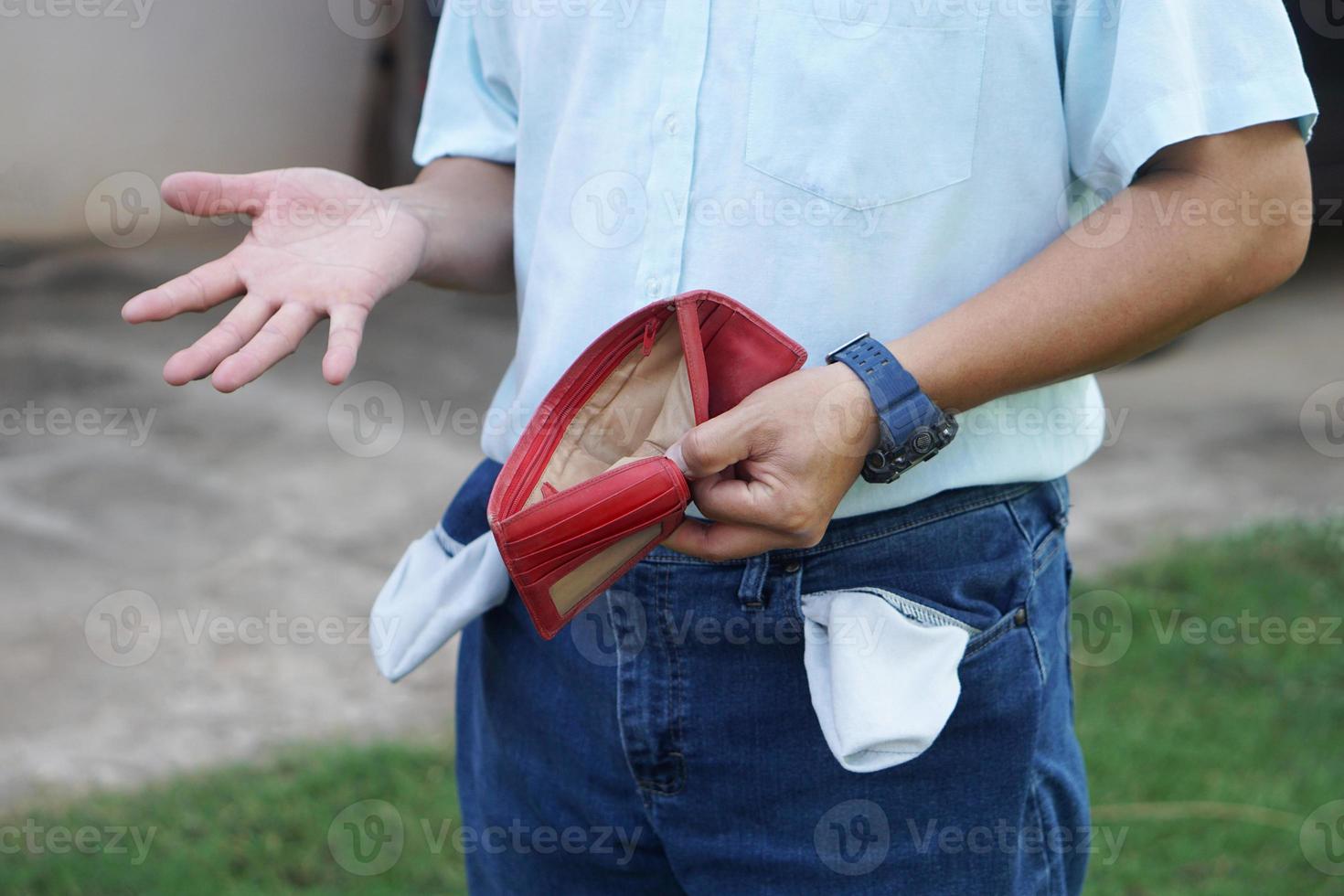 Closeup man holds empty red wallet to show that he has no money. Concept, Poor, bad economic crisis. Financial problems. Broke or less money at the end of month. photo