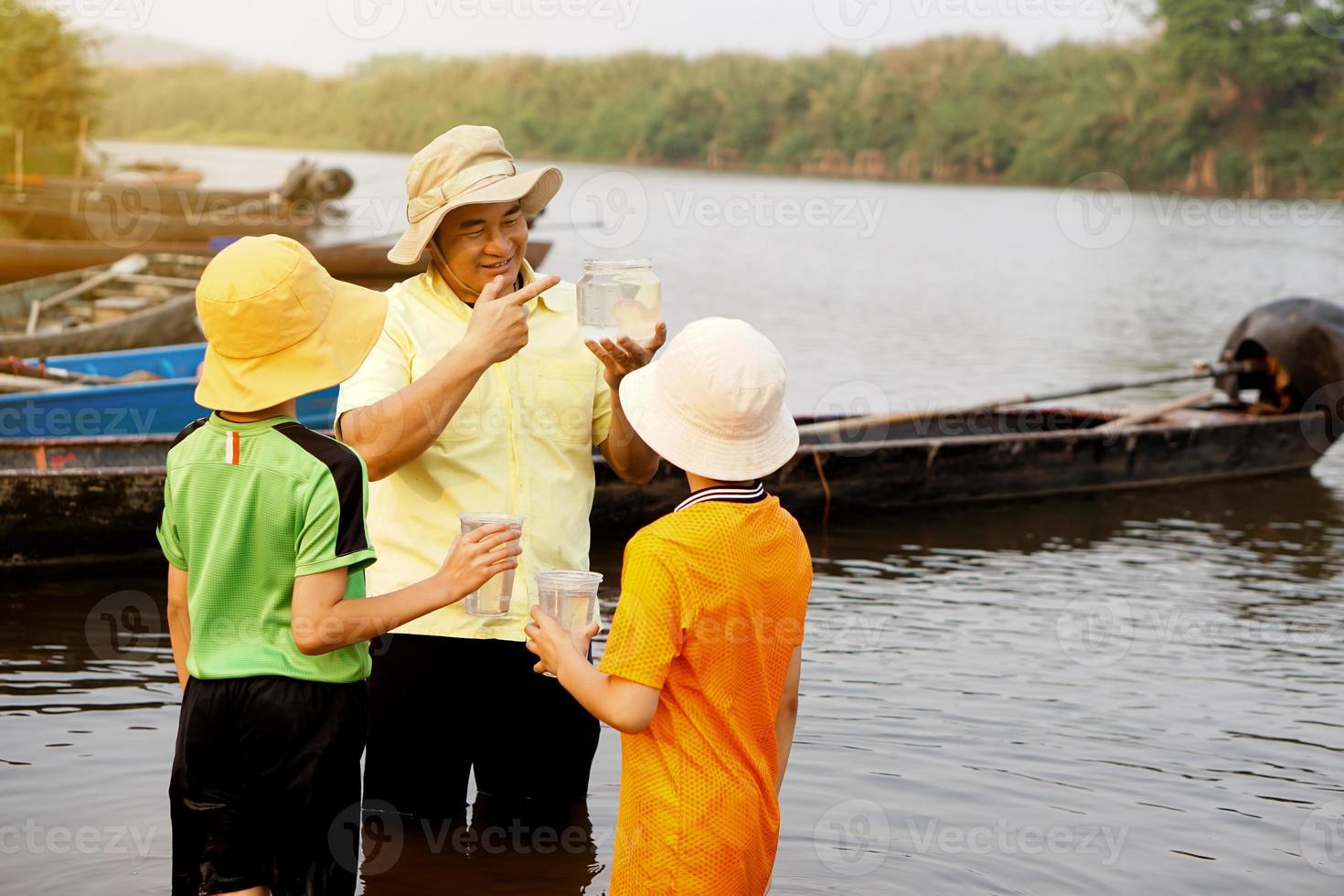 Asian man teacher is teaching his students outdoor, study ecology subject, explore water from nature source. Concept,Education. Learning by doing. Life experience. photo