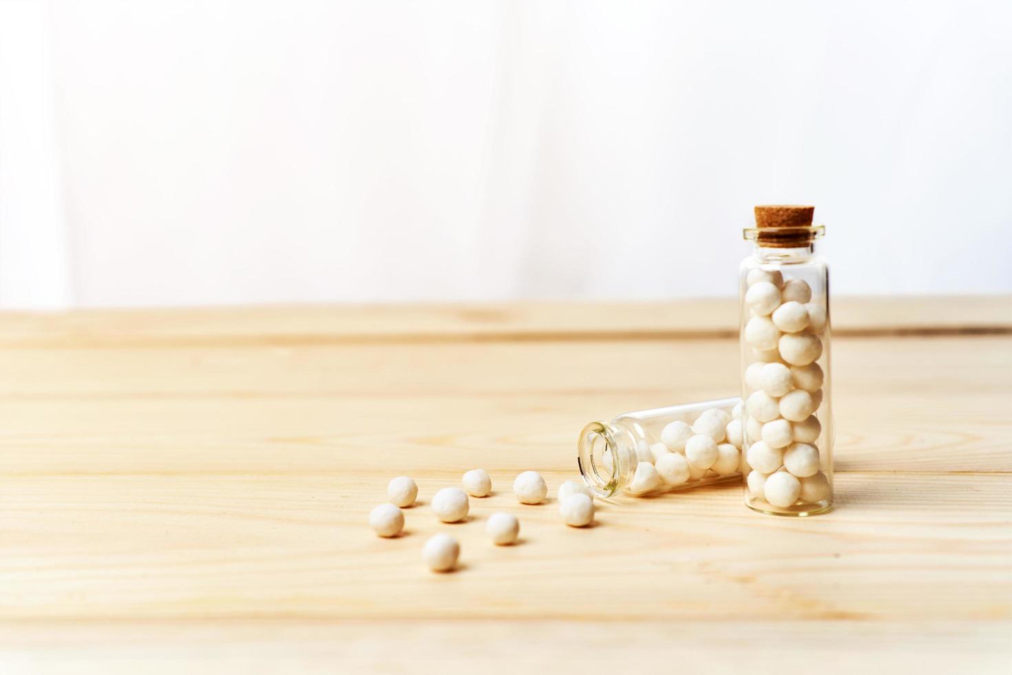 concept of homeopathic pills in bottles on wooden table white background photo