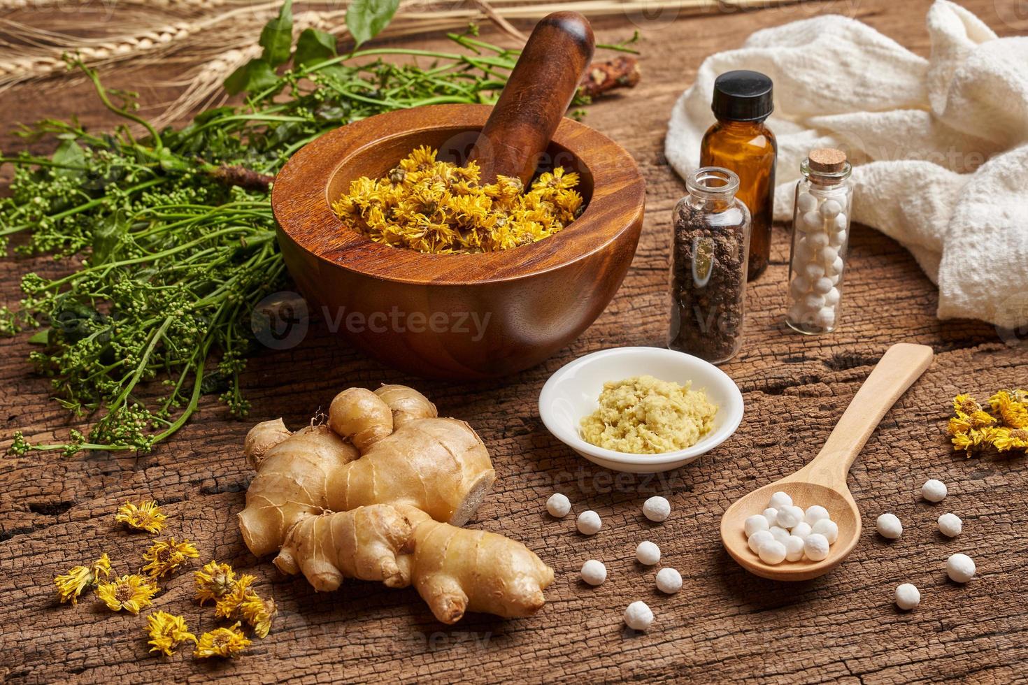 concept of homeopathic pills in a wooden spoon and bottles with the herb in a mortar with a pestle on wooden table background photo