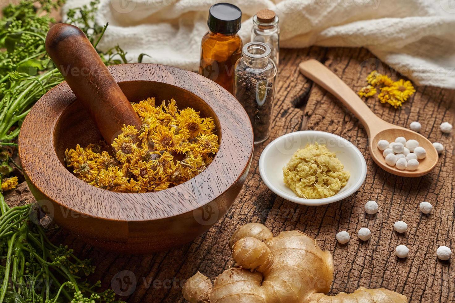 concept of homeopathic pills in a wooden spoon and bottles with the herb in a mortar with a pestle on wooden table background photo