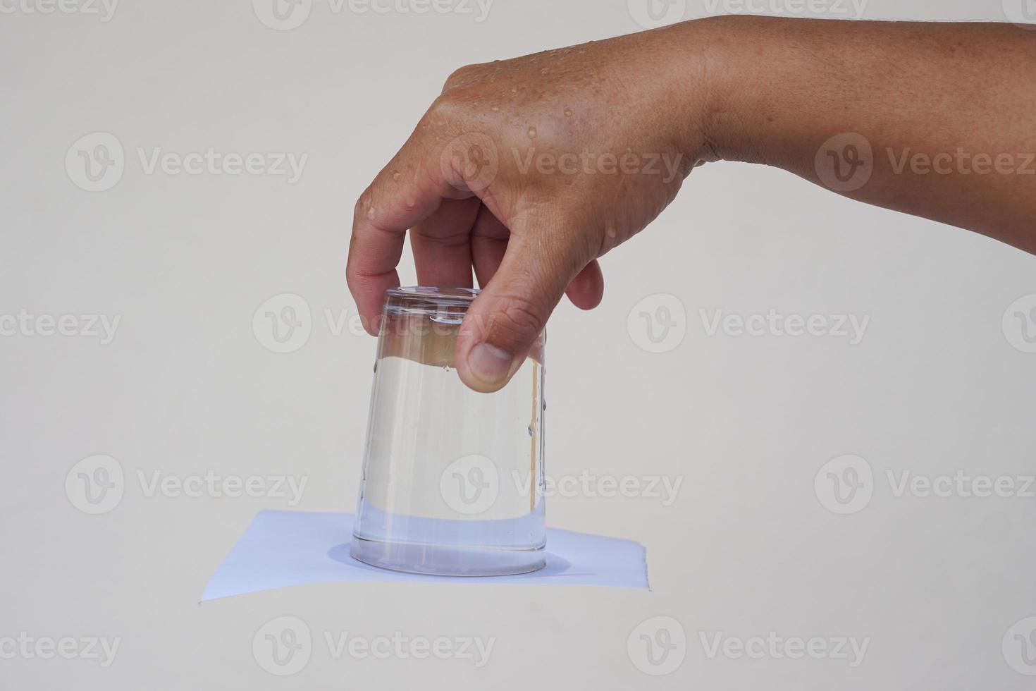 Closeup hand hold and turn  a glass of water over down. covered the glass with paper. Concept,  science experiment about air and liquid pressure. Easy science subject activity, education. photo