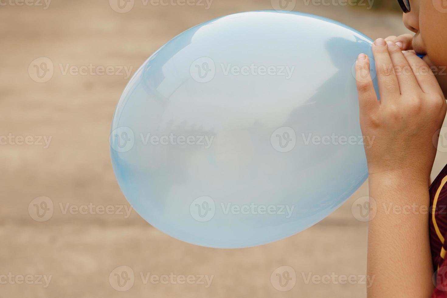 Closeup boy is blowing pink balloon, inflates  air to balloon Concept, children play, toy and equipment to play fun games or prepare party. photo