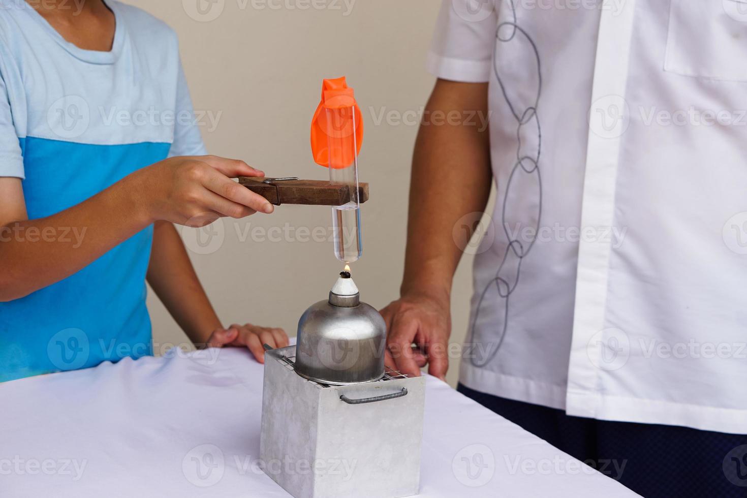 Closeup student is doing science experiment about reaction of air in ballon from boilng water in test tube on lantern. Concept, Science camp activity. Learning by doing. photo