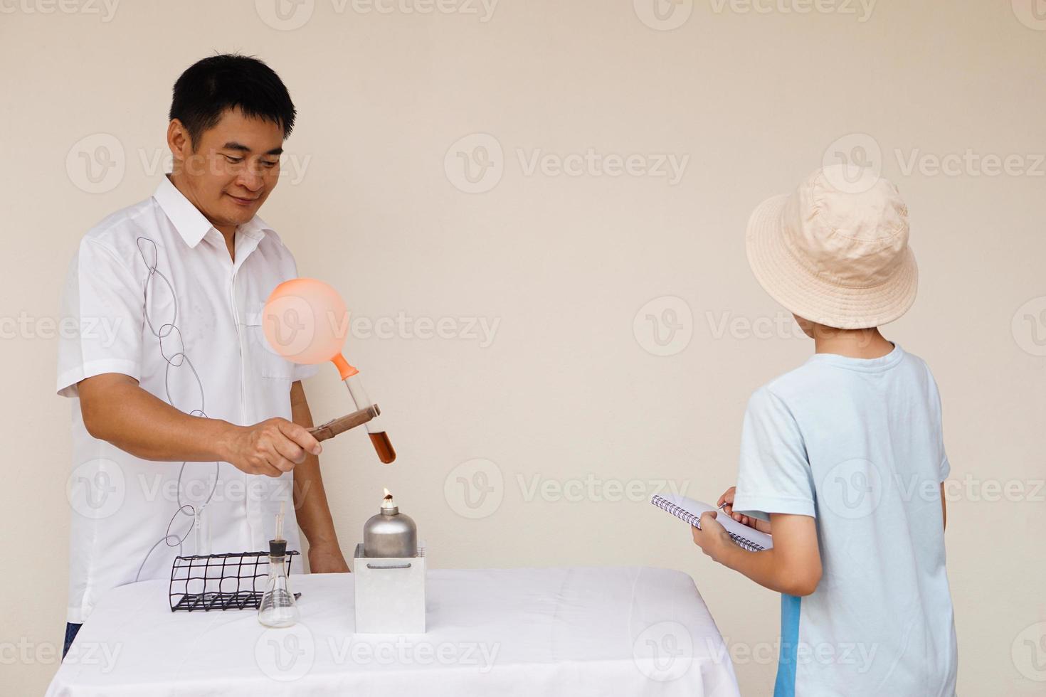 Asian man teacher is demostrating science exeriment about reaction of balloon on test tube is burned from lantern for his student. Science activity. photo