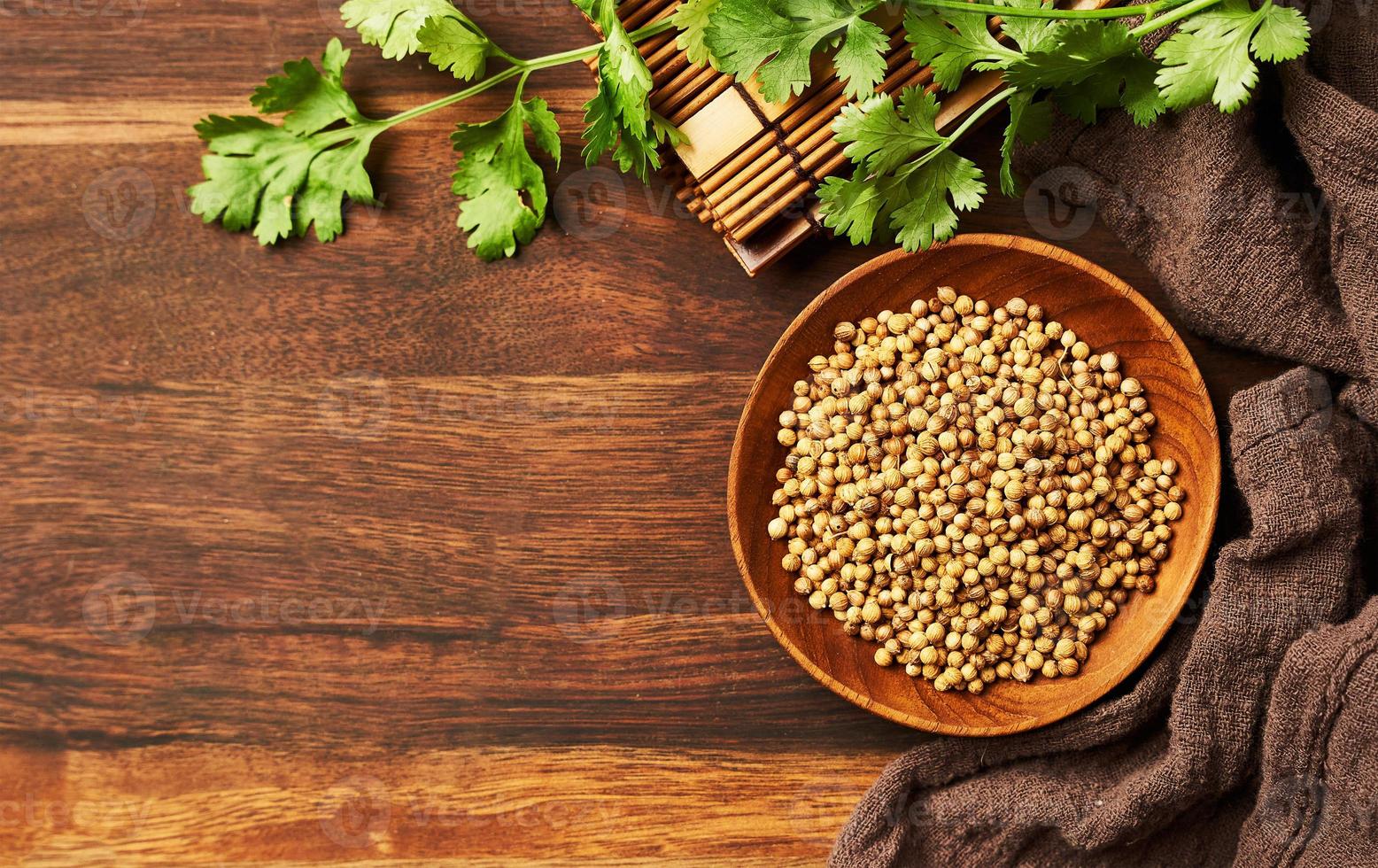 top view dry coriander seed spice in a wood dish and leaf or leaves on wooden background with copy space photo