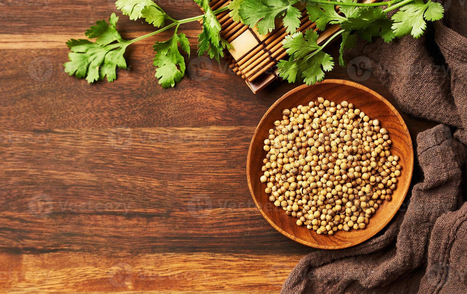 parte superior ver seco cilantro semilla especia en un madera plato y hoja o hojas en de madera antecedentes con Copiar espacio foto