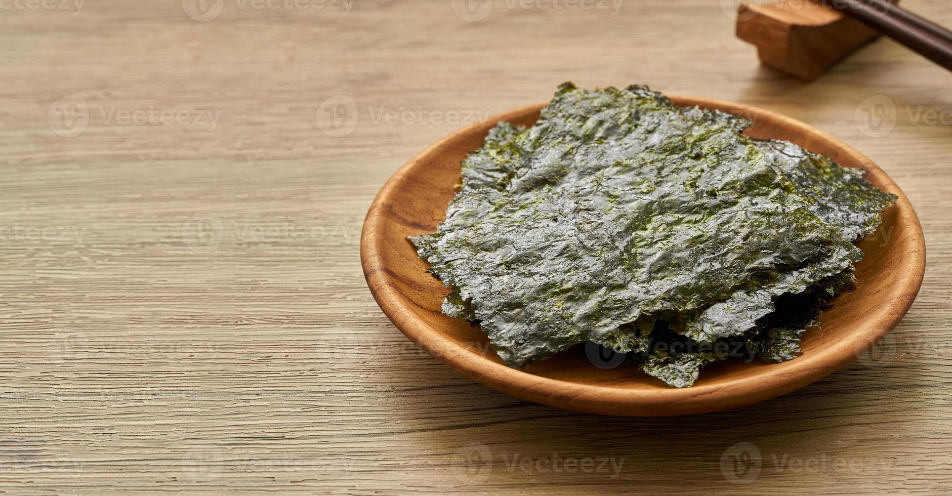 roasted nori laver seaweed snack in wood plate on wooden table background. nori laver seaweed crispy in wood plate on wooden table background. photo