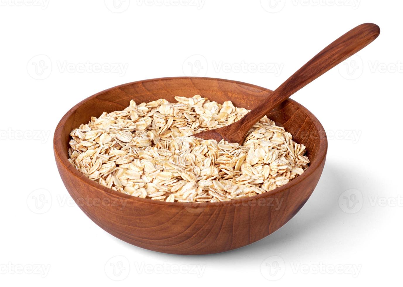 Rolled oats or oat flakes in bowl with wooden spoon isolated on white background with clipping path photo