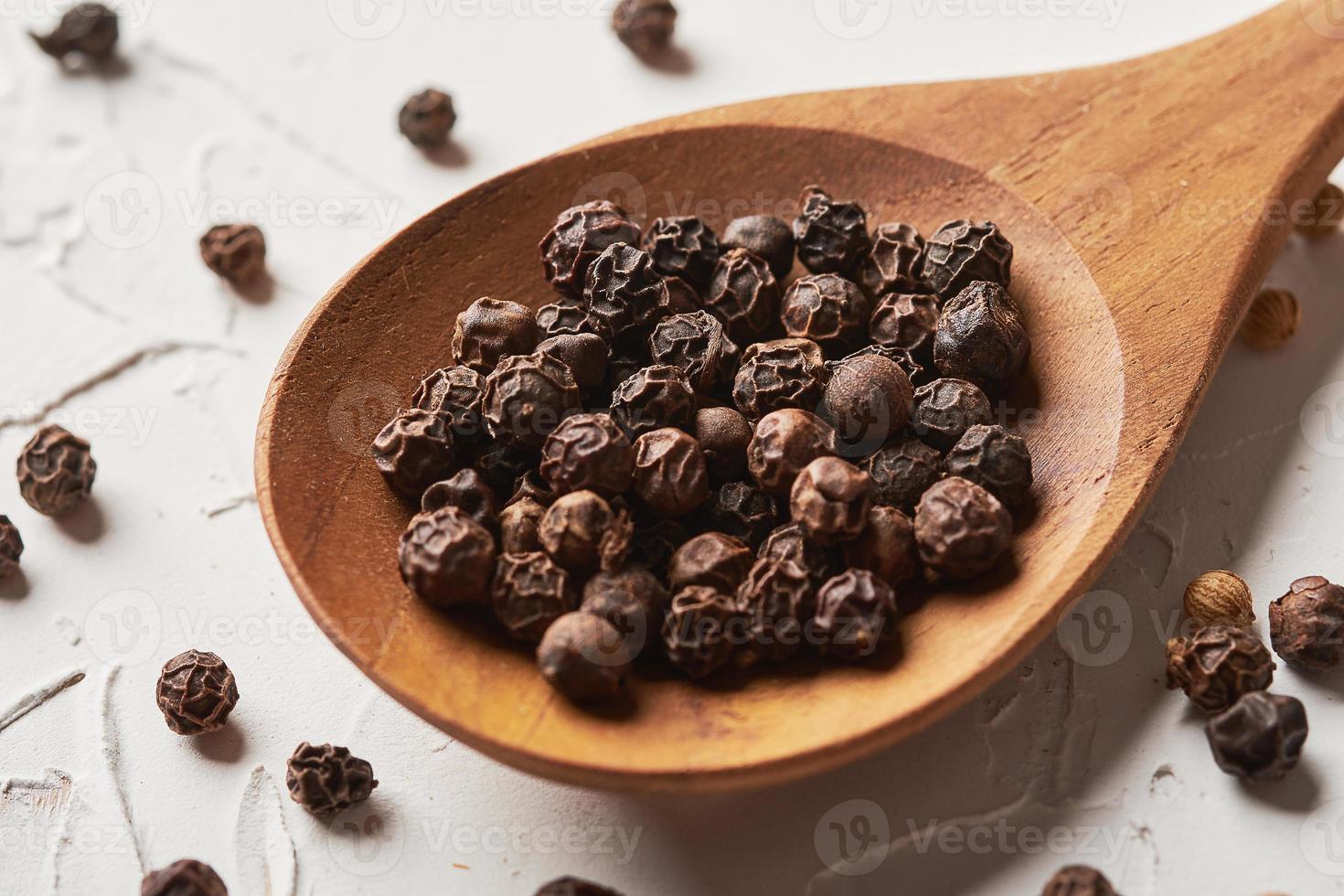 black pepper in spoon on white background photo