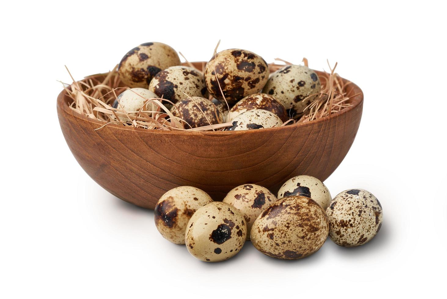 close up quail eggs in wooden bowl and straw nest isolated on white background with clipping path photo