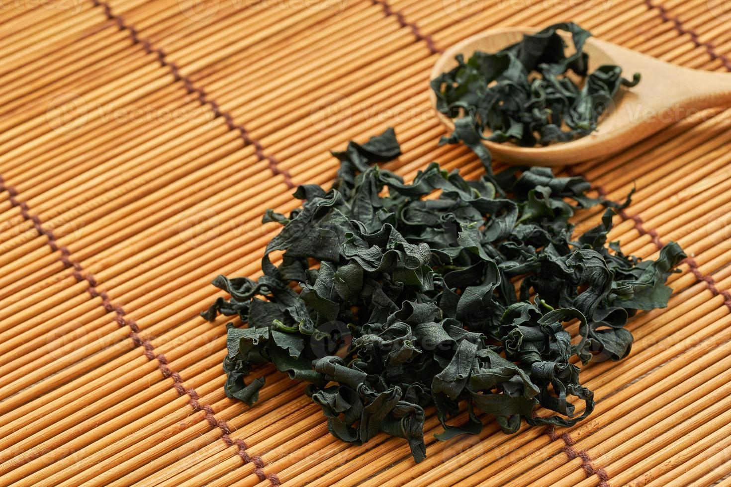 close up dried Laminaria Kelp Seaweed in wood spoon on wooden table Background. dried Laminaria or kelp Seaweed on wooden plate Background. konbu, alga, wakame, kombu photo