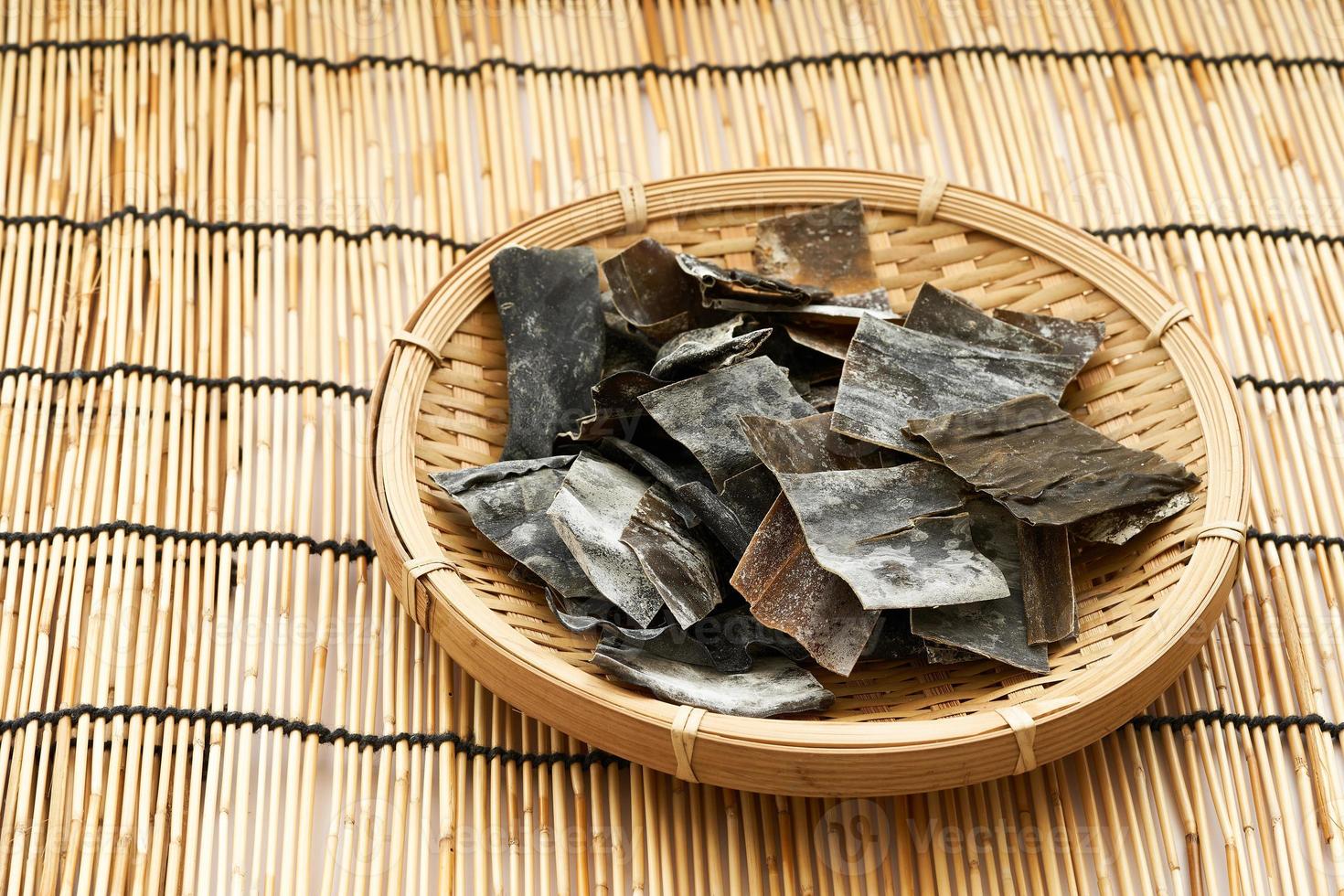 dried Laminaria Kelp Seaweed or kombu slice in wood plate on a Bamboo mat background. dried Laminaria or kelp Seaweed background. konbu, alga, wakame, kombu, kombu photo