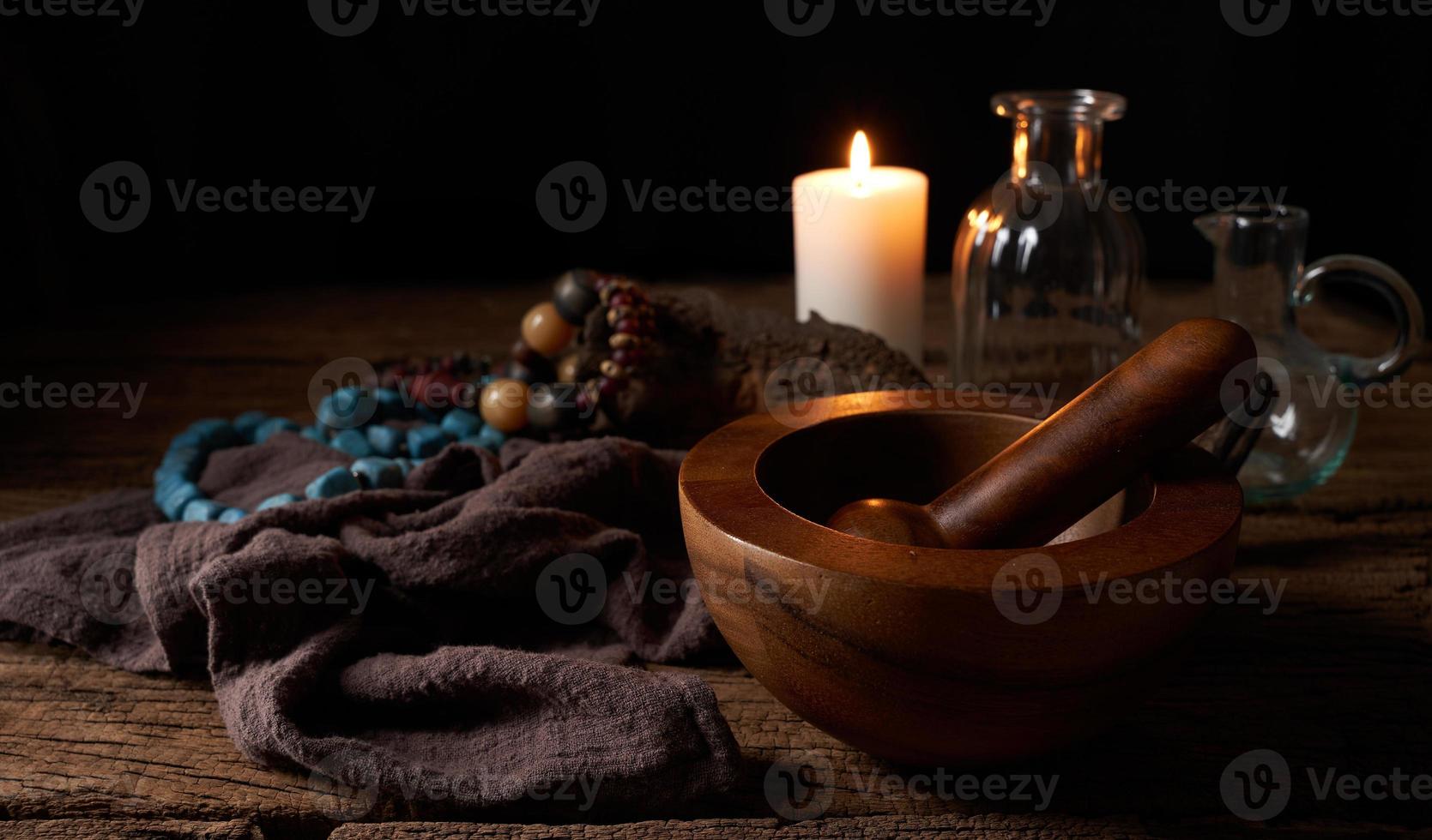 concept of magic potion n a wooden table and white candle with a mortar on dark background. macabre, witchcraft photo