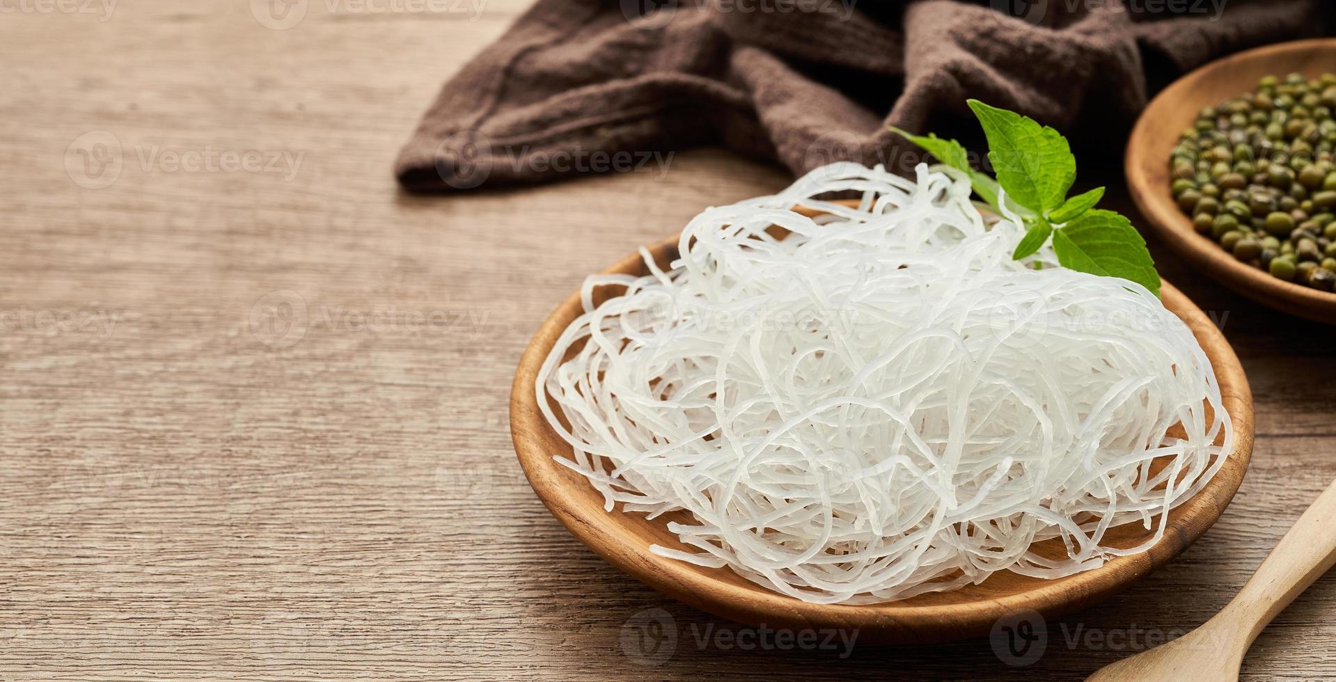 Asian vermicelli or cellophane noodles and mung green bean in wooden plate on wood table background. glass noodle photo