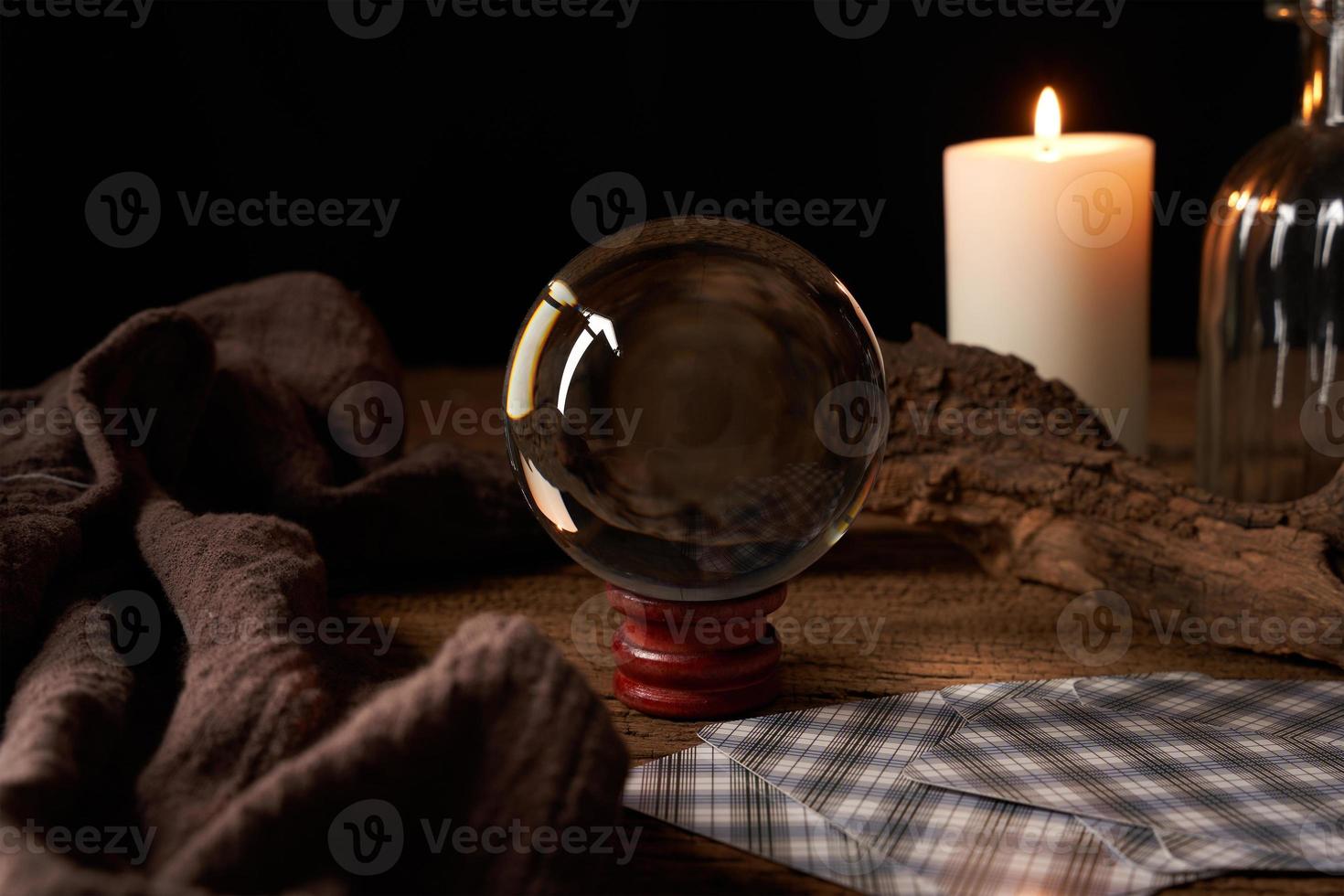 concept of fortune-telling on a wooden table and white candle with a crystal ball and tarot cards on dark background photo