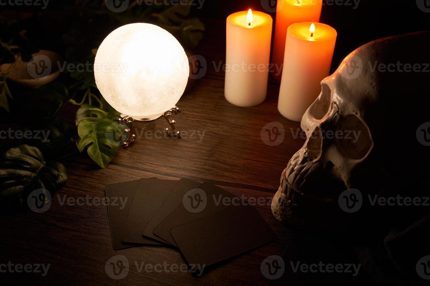 adivinación en un de madera mesa y un blanco vela con un cristal pelota y tarjetas en oscuro antecedentes. predecir, predicción, horóscopo, macabro, brujería, cráneo foto