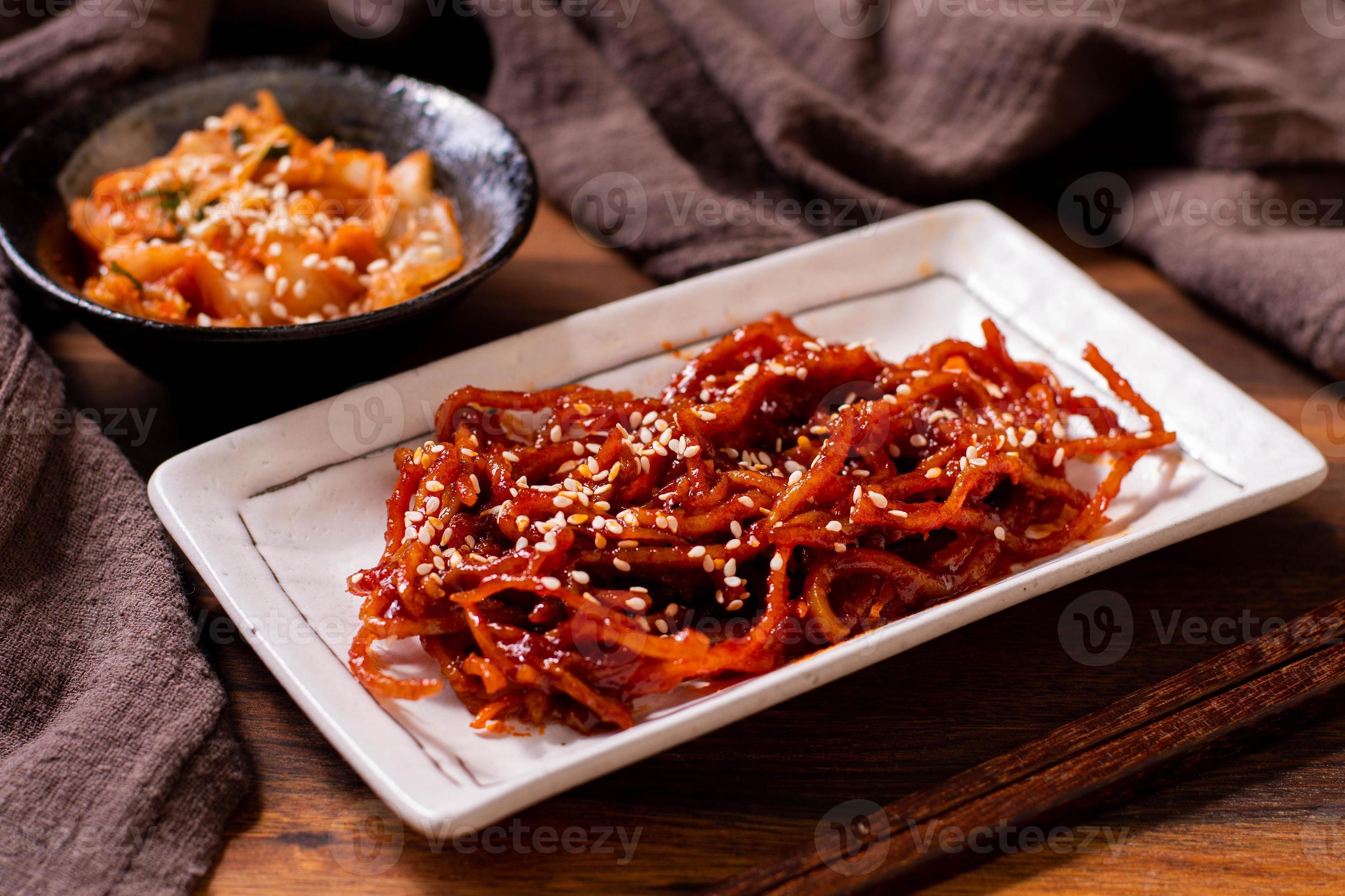 Seasoned dried shredded squid ojingeochae muchim with kimchi on wood