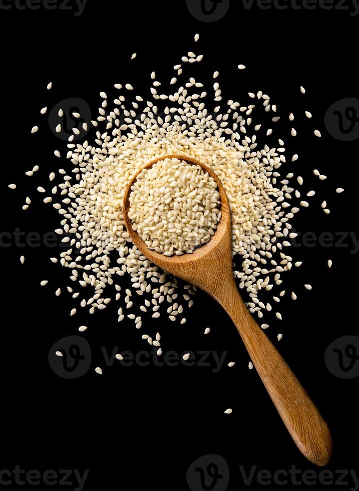 white sesame seeds with spoon on black background. organic natural sesame seeds with spoon on black background. toasted sesame seeds with spoon on black background photo