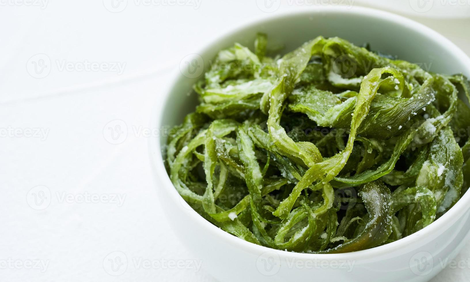 heap of fresh Korean salted seaweed salad stem side dish or Miyeok Julgi Bokkeum in white bowl on white background. Laminaria or Kelp Seaweed stem photo