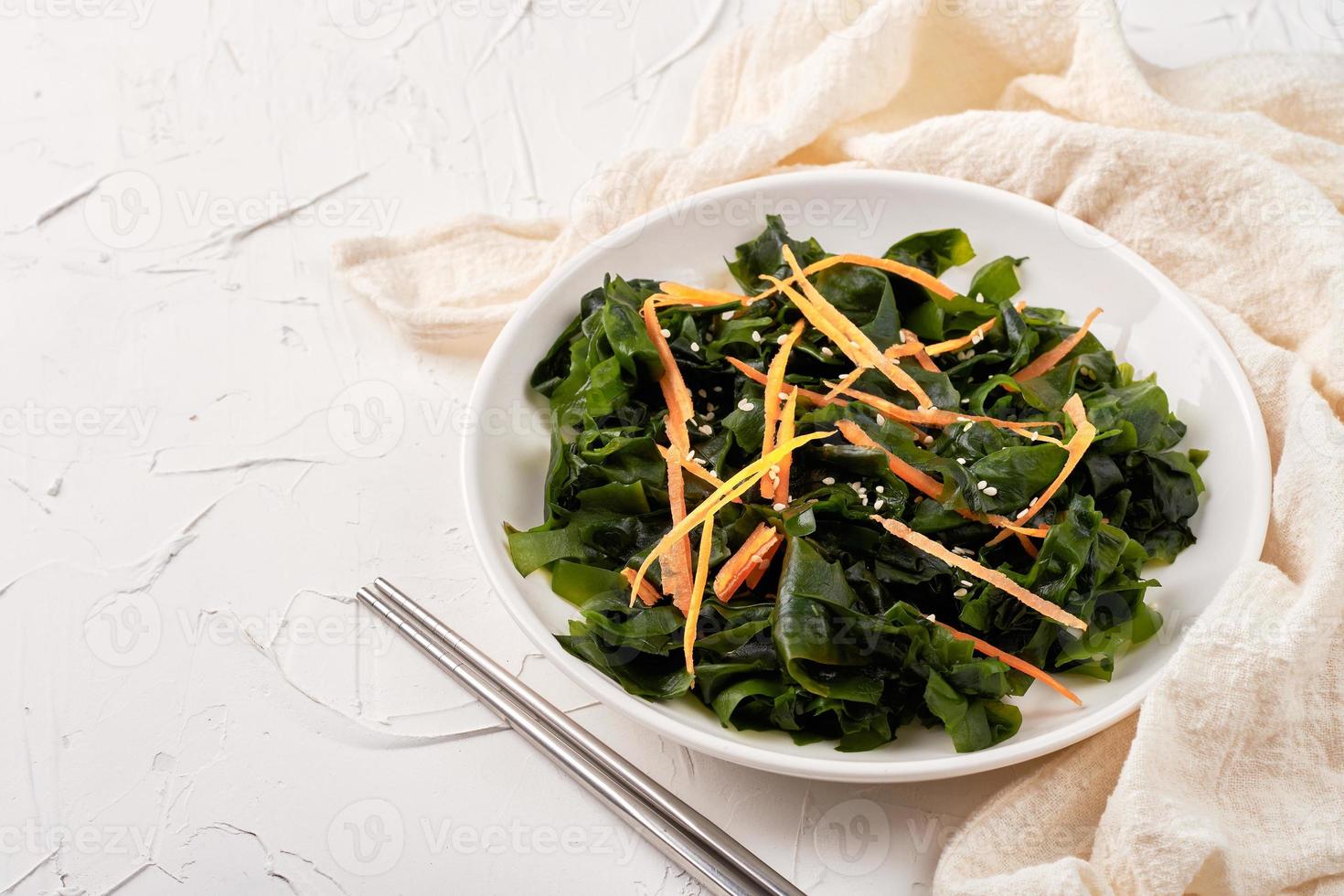 homemade seaweed salad or kelp in a white dish on white table background photo