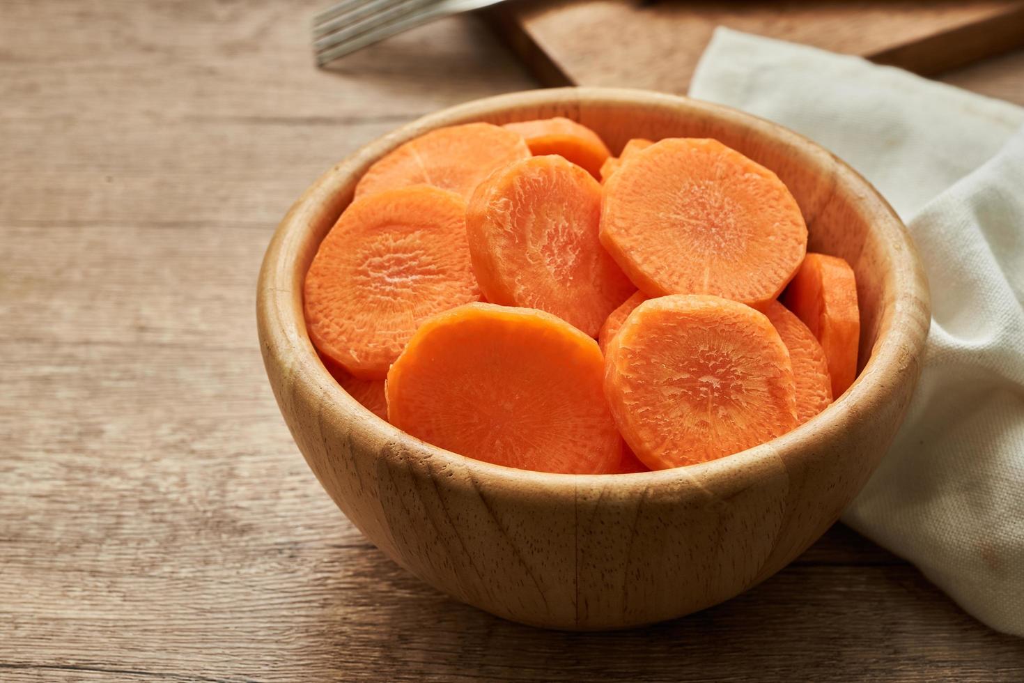 chop round carrot on wooden plate on wood table background photo