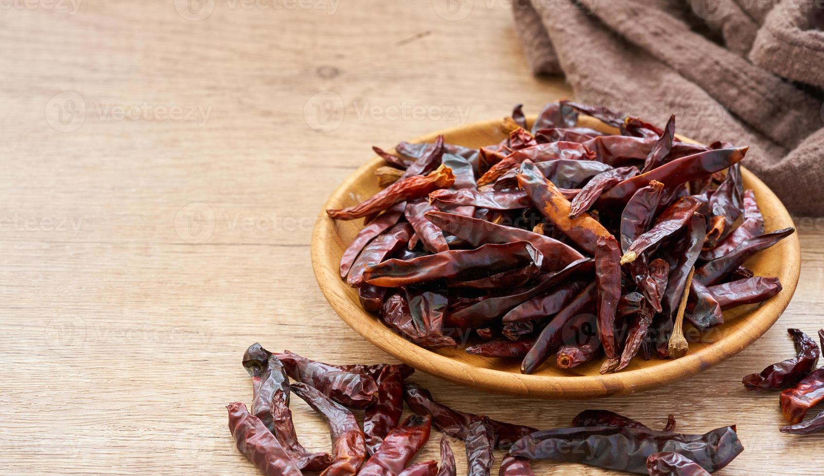 close up pile of dry red chilli chili pepper in wood plate on wooden table food spices background. chilli, chili, pepper photo