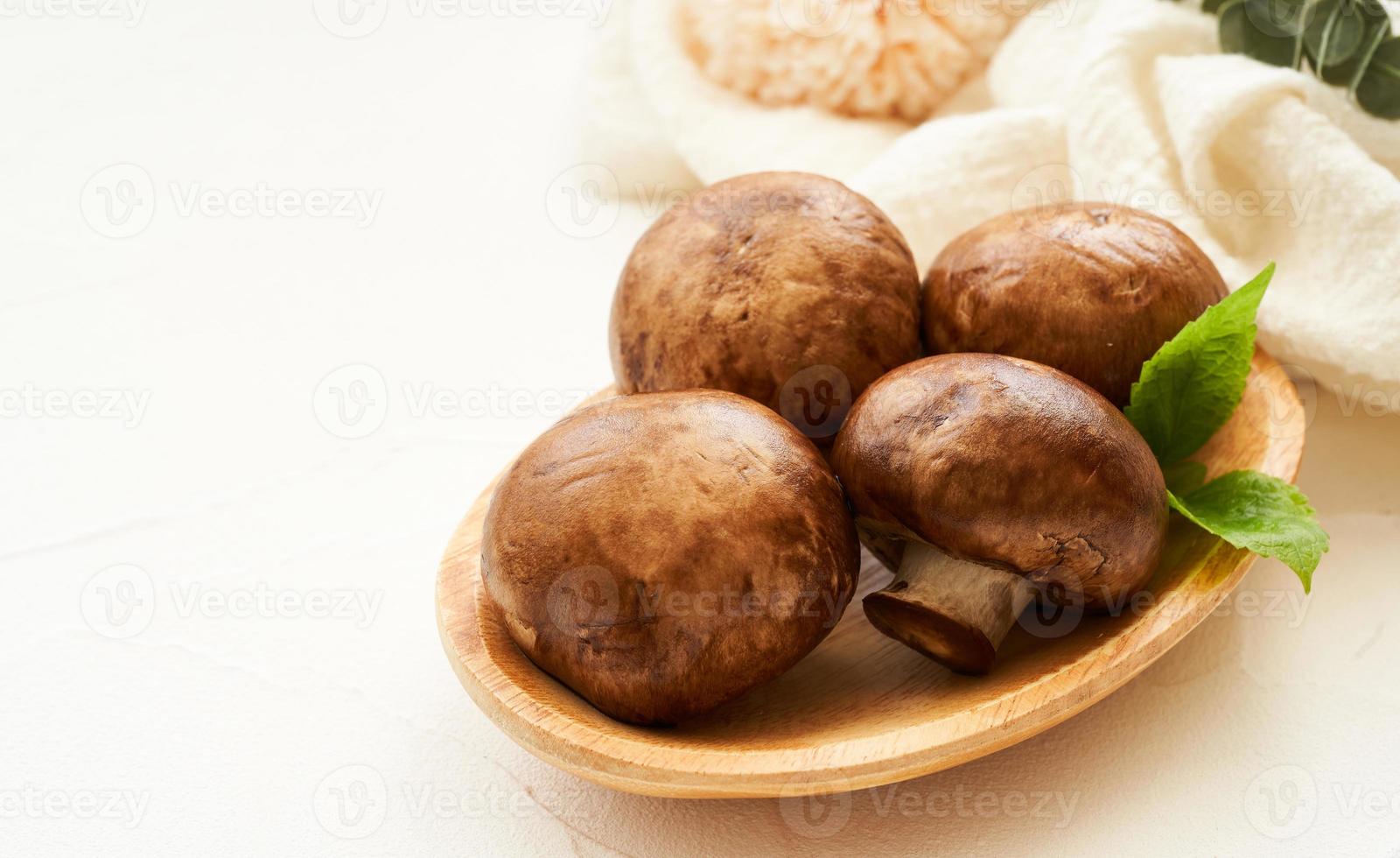 brown champignon button mushroom and green leaf in wood bowl on white table background. pile of brown champignon button mushroom photo