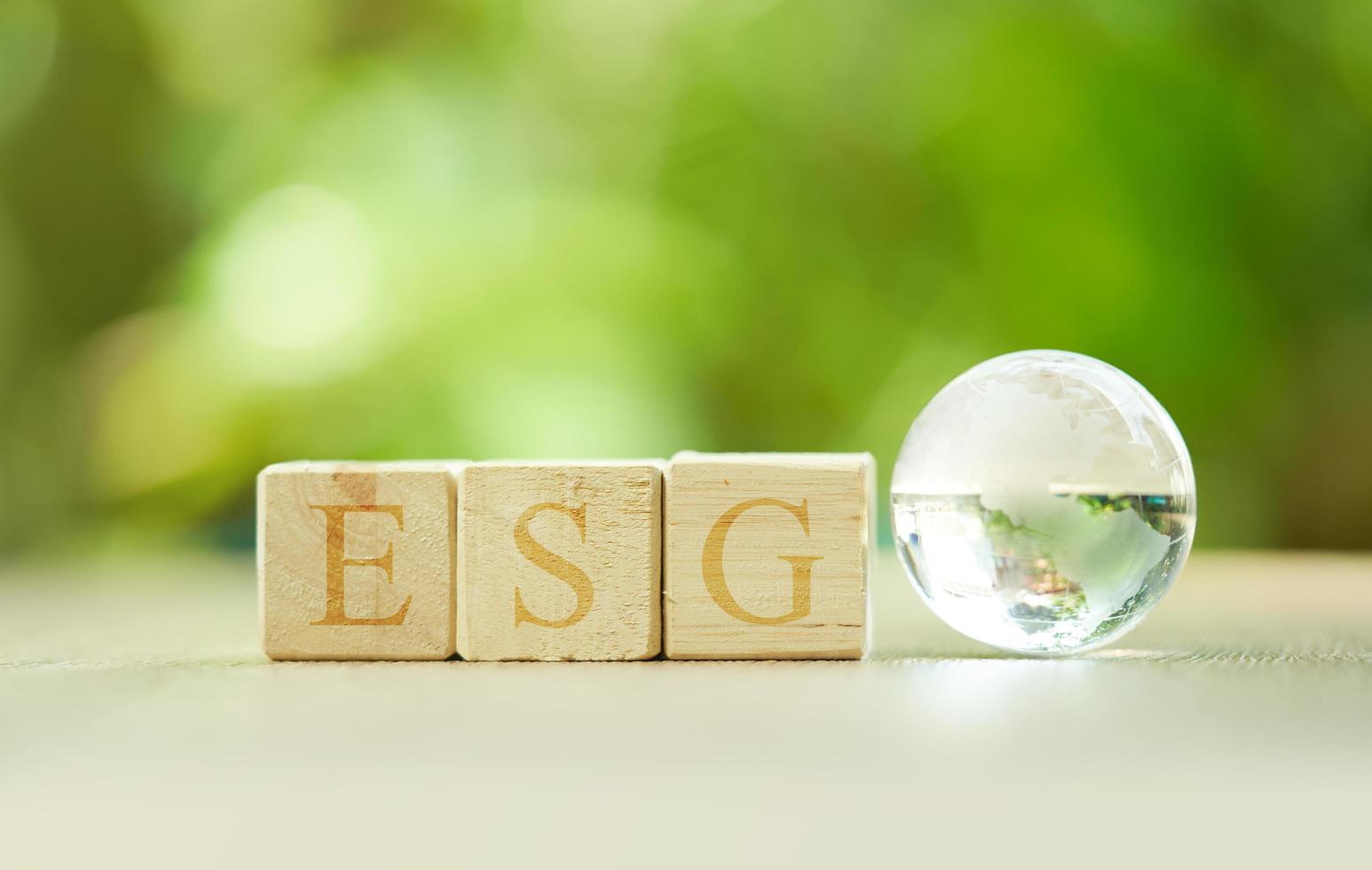 glass or glasses world ball with word ESG wood block concept for environmental eco, social, and governance in sustainable and ethical business on a table green background. globe, earth photo