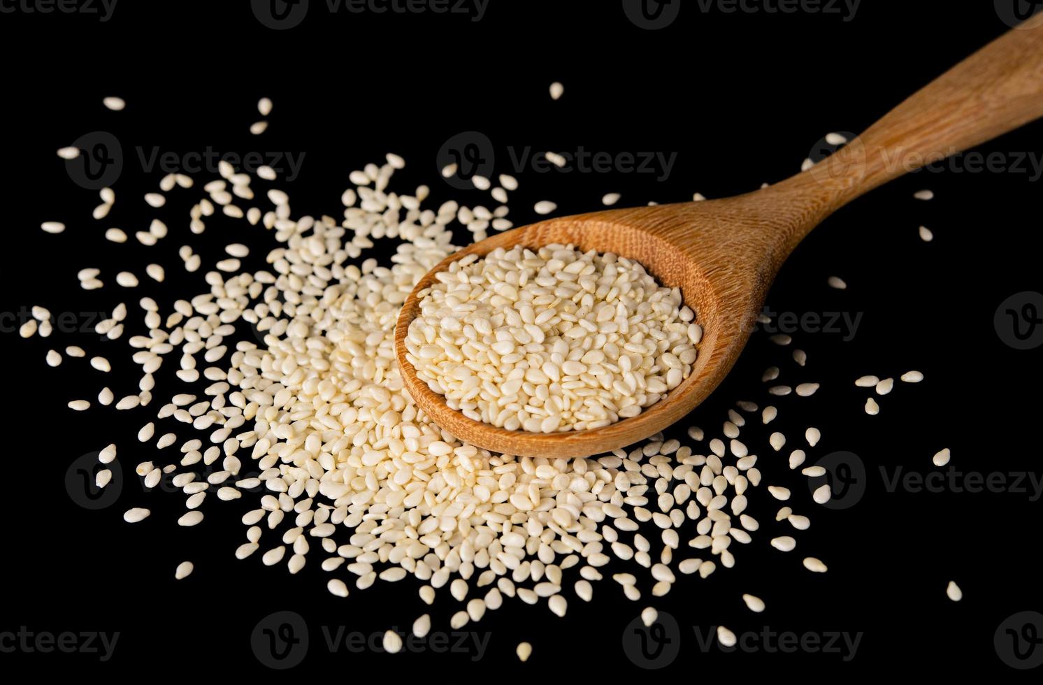 white sesame seeds with spoon on black background. organic natural sesame seeds with spoon on black background. toasted sesame seeds with spoon on black background photo