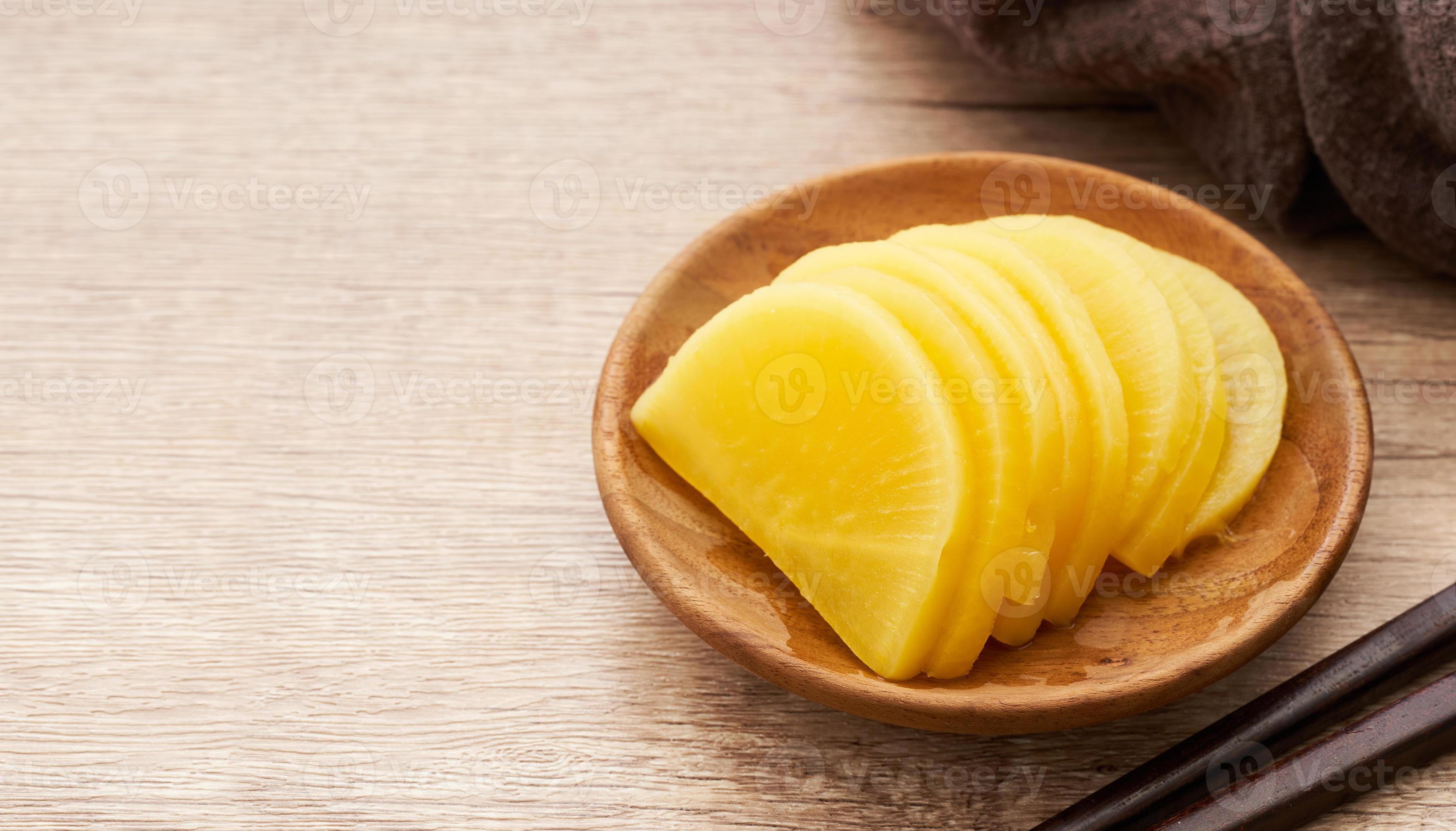 Korean yellow pickled radish or Danmuji side dish in wood bowl on