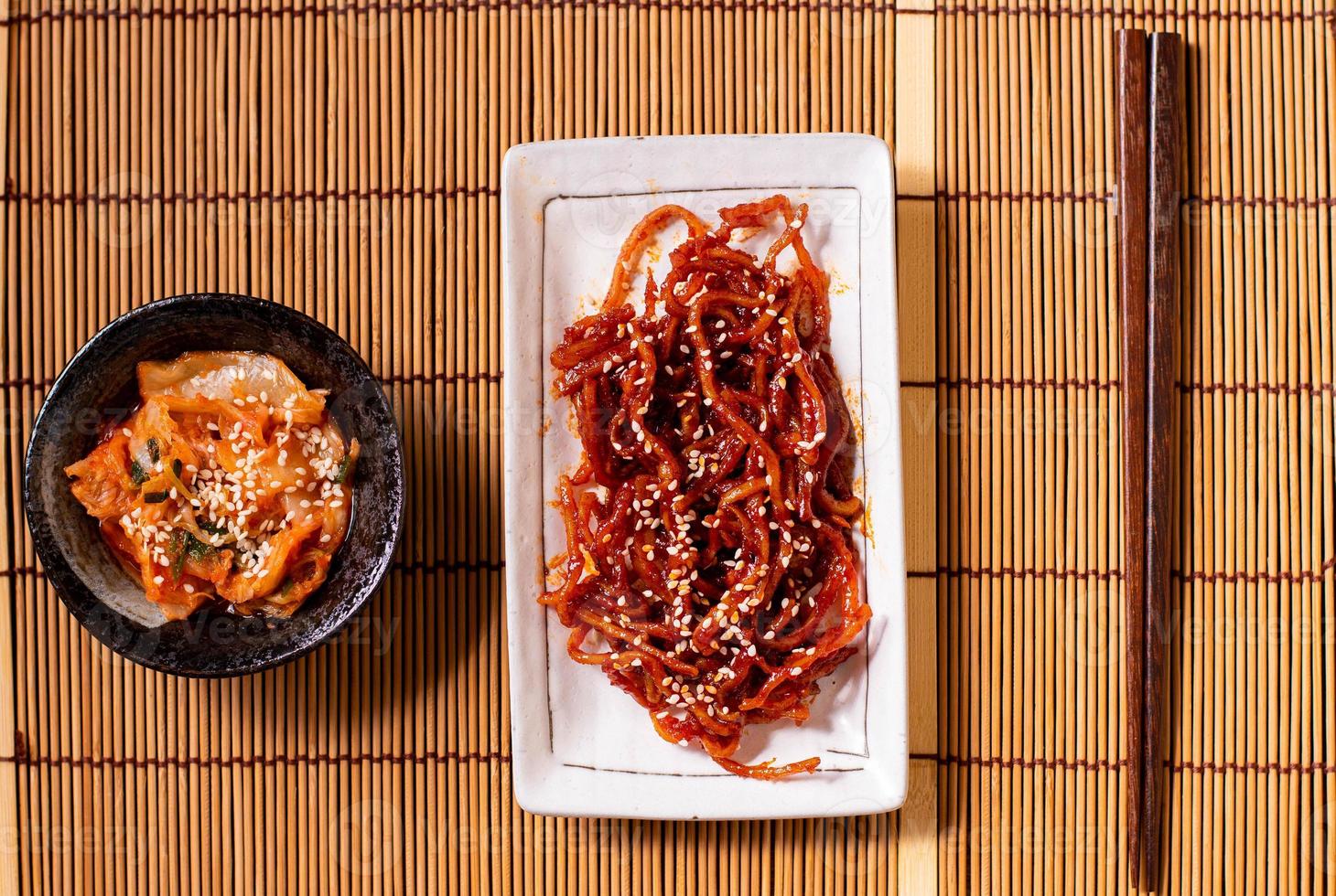 Seasoned dried shredded squid ojingeochae muchim with kimchi on wood