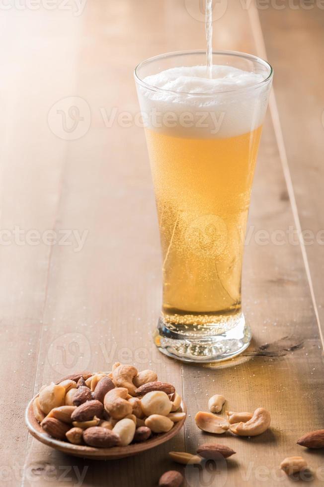 Cold beer with cocktail nut on wood. photo