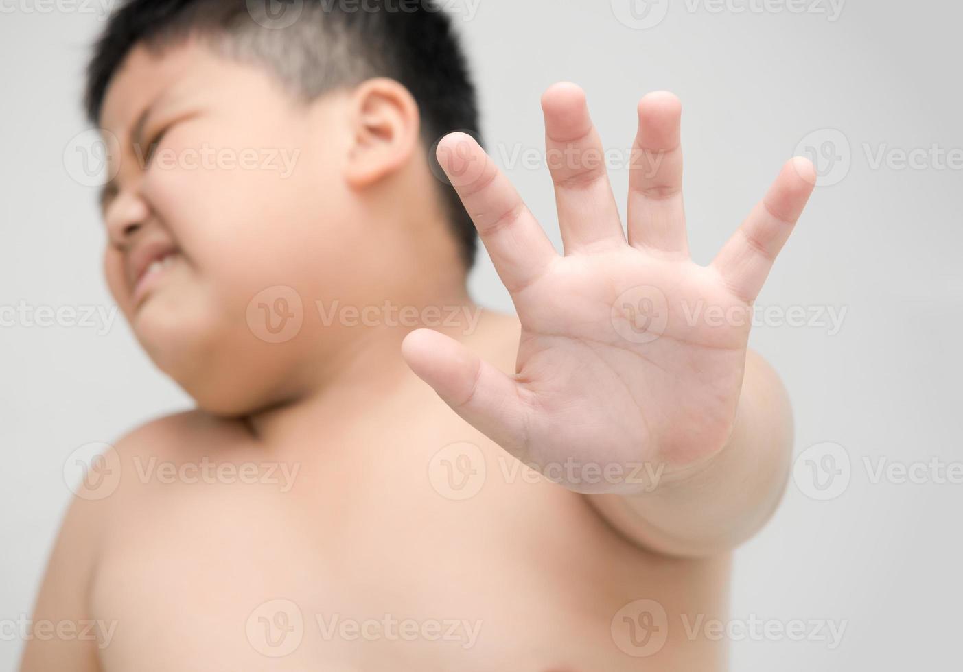 obese boy showing stop gesture on gray background photo