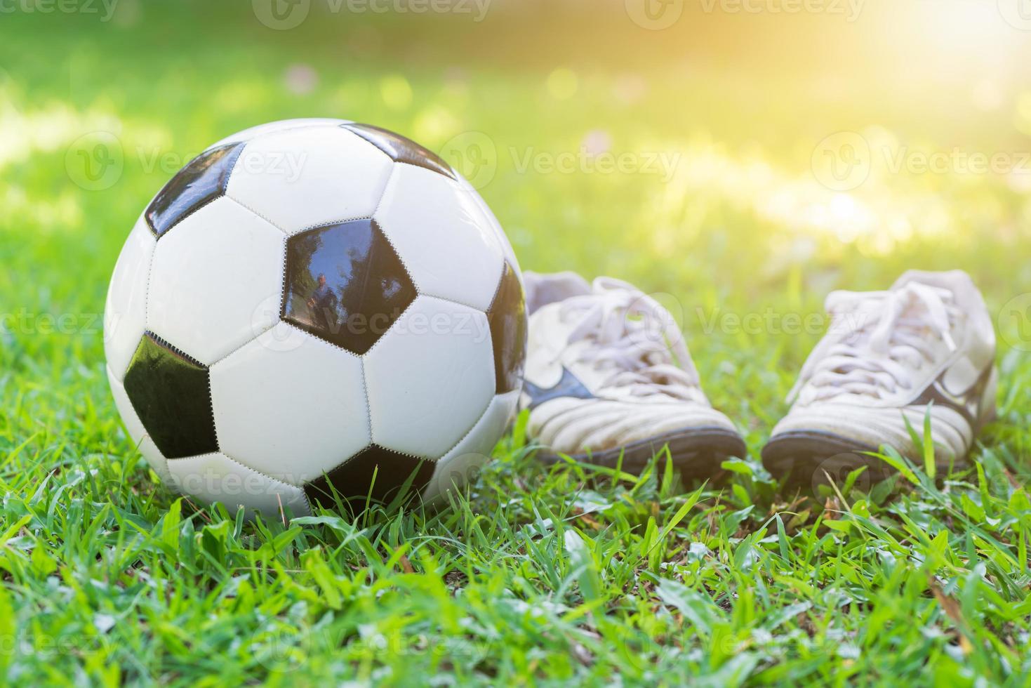 football on green grass and stud shoe with sun light photo