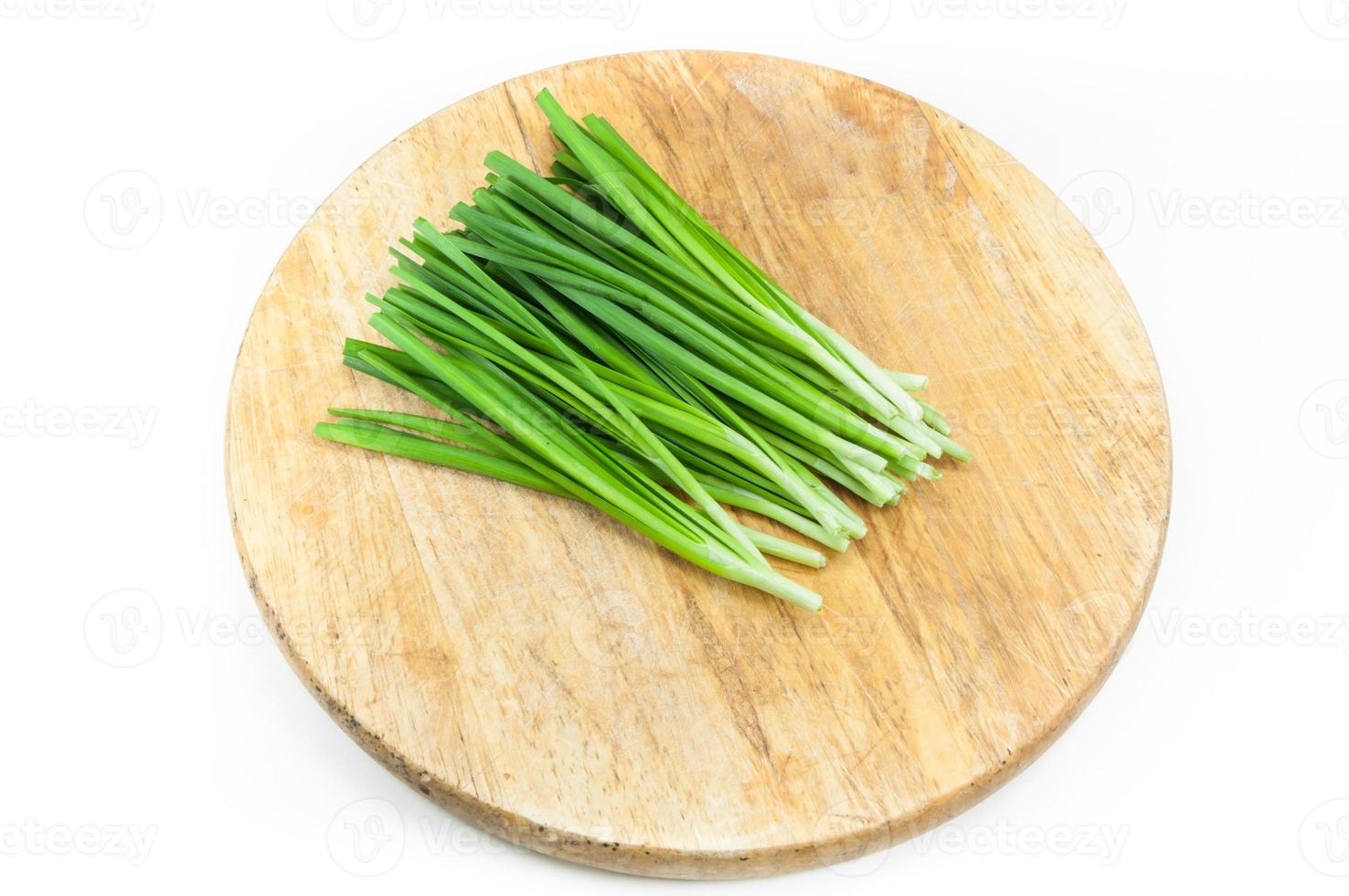 green onions on a wooden chopping board on white background photo