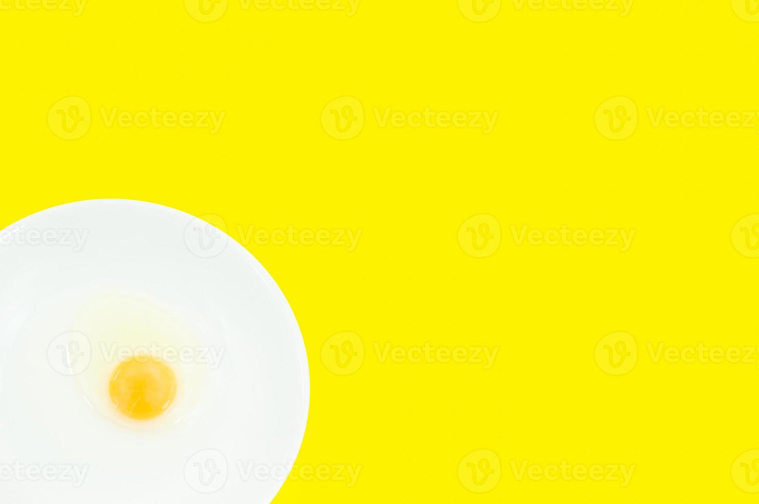 Raw egg yolks in a white bowl isolated on a yellow background, To prepare for a high protein diet has helped in the growth of a person's body photo