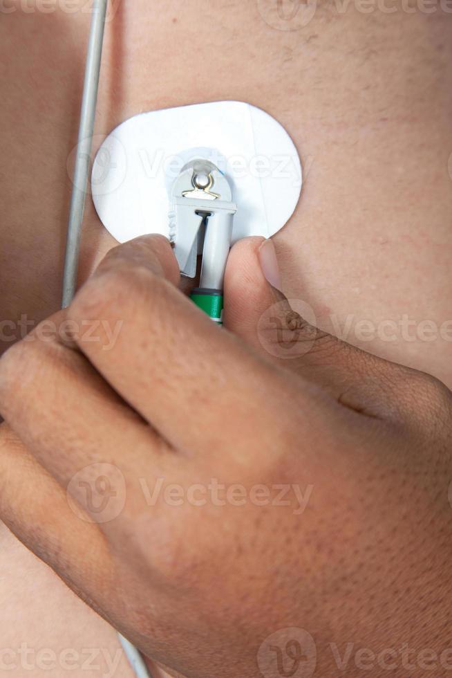 Nurse placing an electrode on patient's chest photo