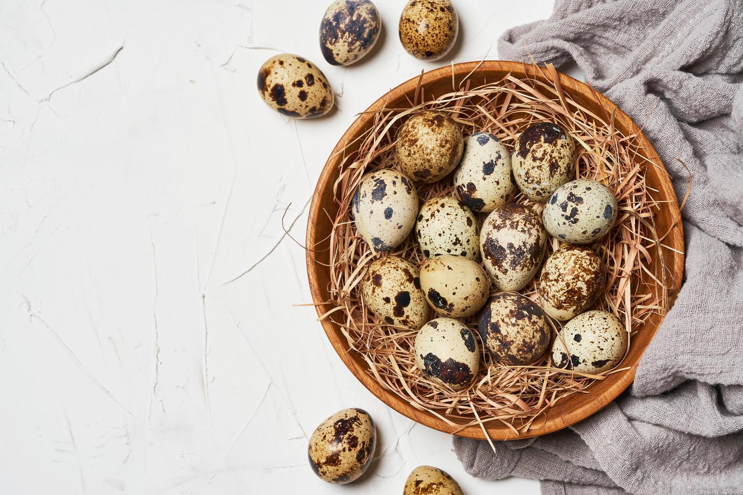 top view quail eggs in wooden bowl on white table background photo